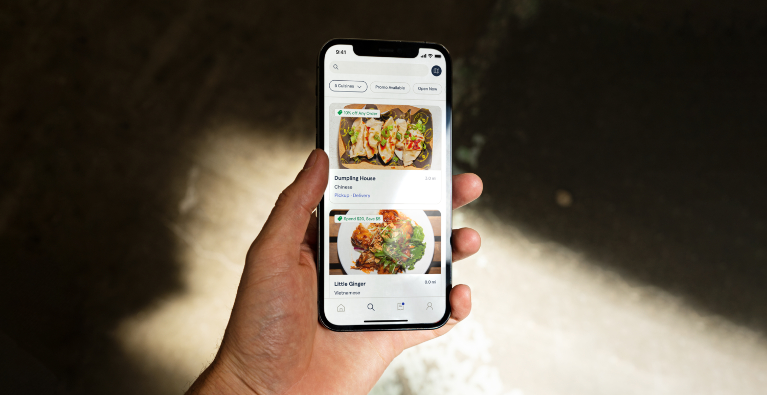 A person holding a mobile phone. On-screen, the user is browsing through a restaurant's mobile menu.