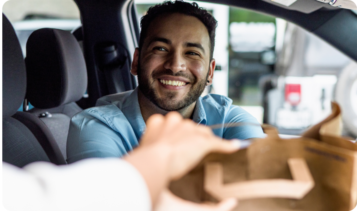 A person receives their curbside pickup order through the passenger window