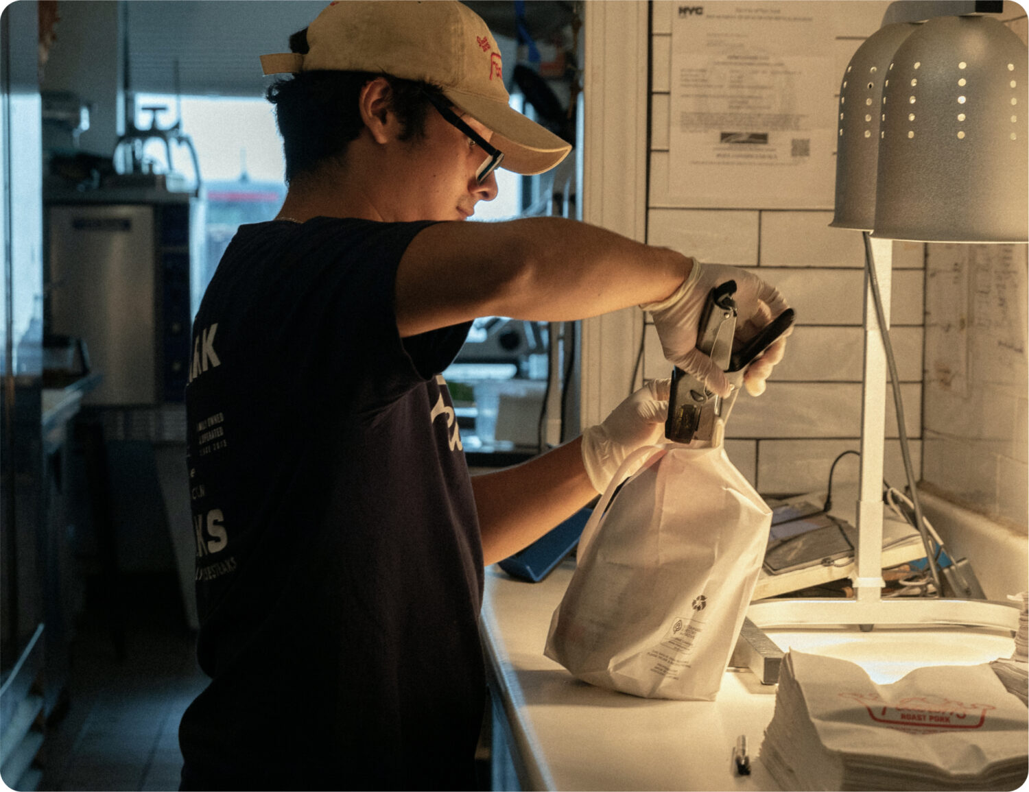 A restaurant employee stapling a takeout bag closed.