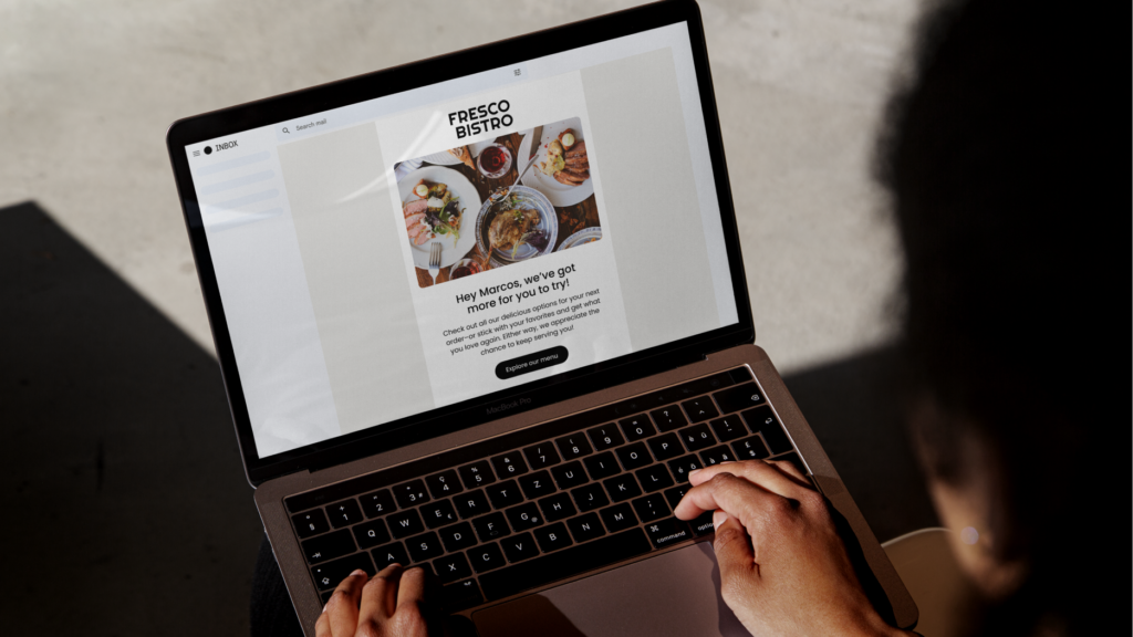 Lifestyle photo of person typing on laptop showing restaurant email campaign with subject line Hey Marcos, we’ve got more for you to try.