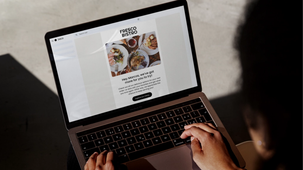 Lifestyle photo of person typing on laptop showing restaurant email campaign with subject line Hey Marcos, we’ve got more for you to try.