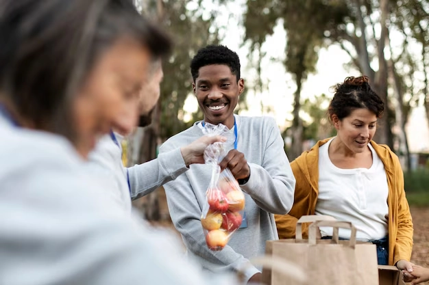 person passing bag of apples to another person