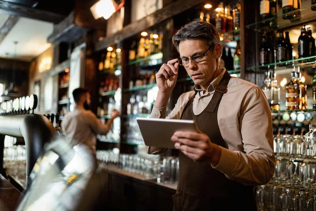 bartender behind bar looking at tablet