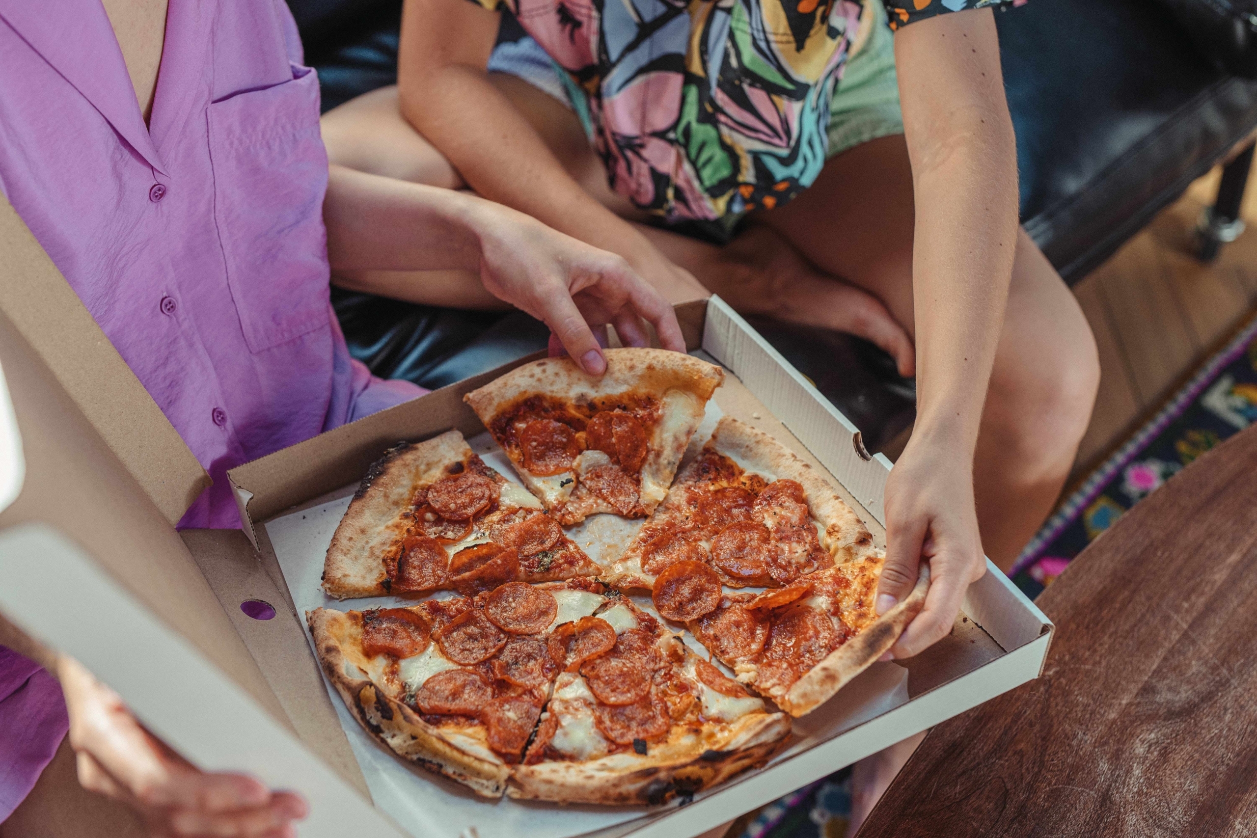 close up of people grabbing pizza