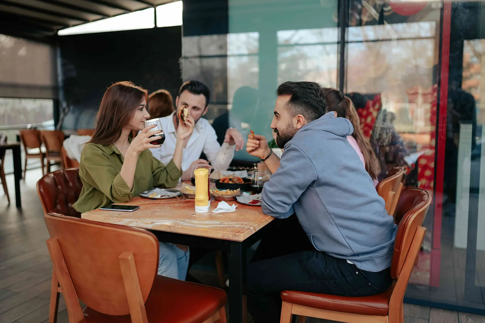 Four people sitting at a restaurant table, eating and talking together.