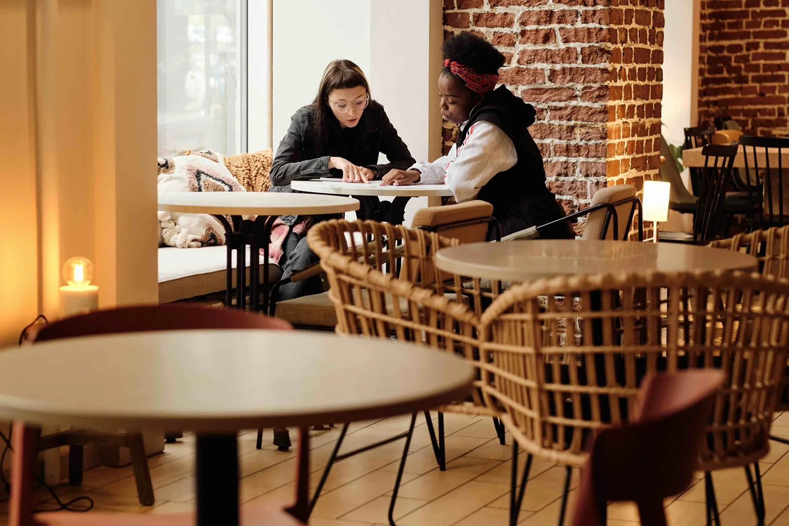 Two people sitting at a café table, looking at a tablet together.