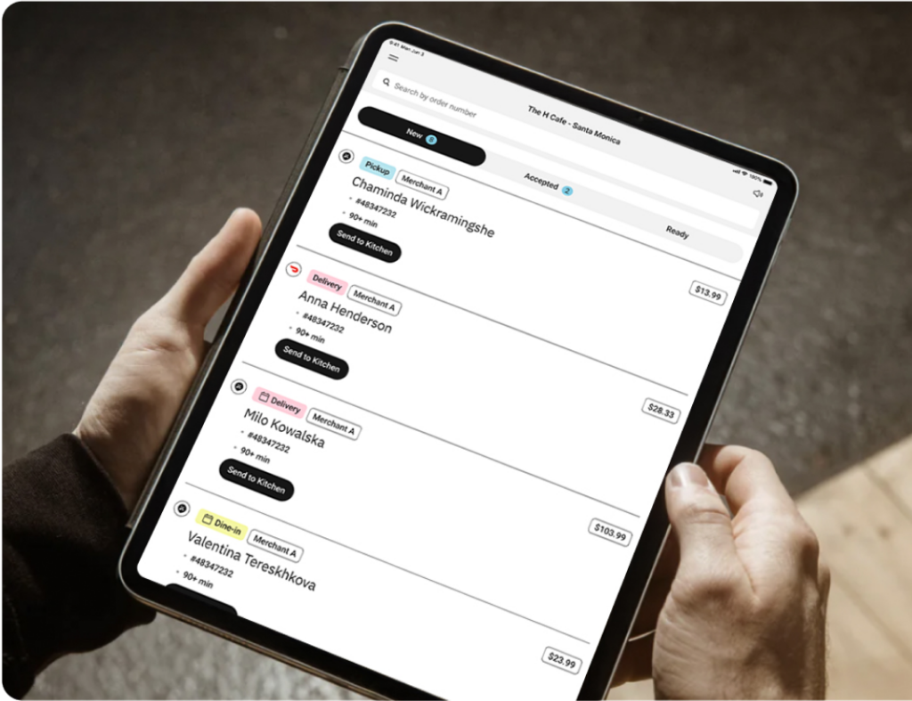 Close up of hands holding a tablet showing a list of incoming orders.
