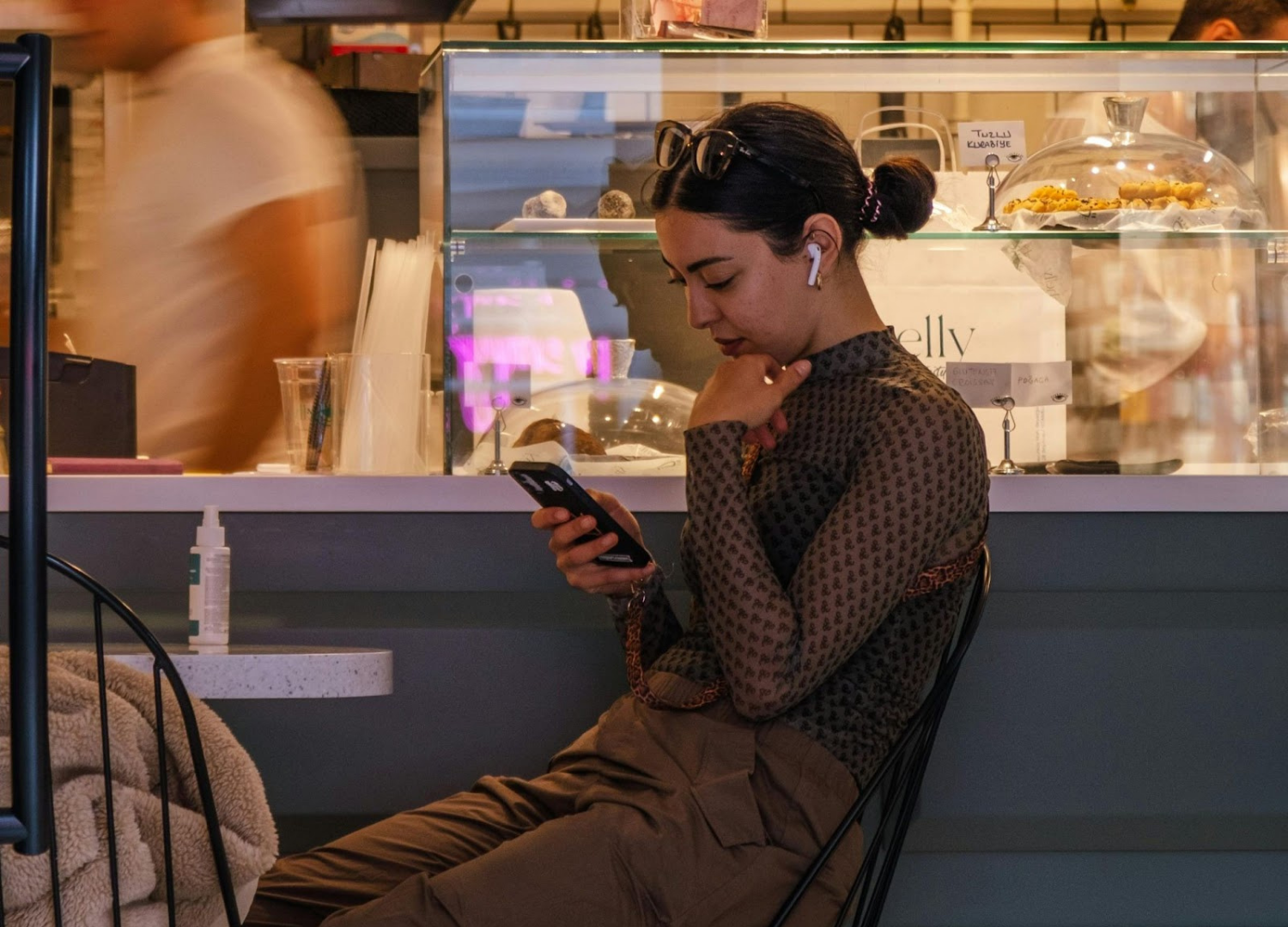 Woman holding and looking at a smartphone in a busy cafe