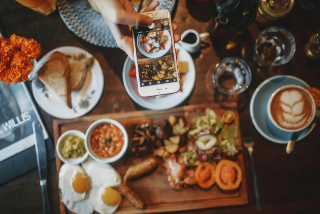 overhead view of phone taking picture of table of food