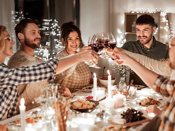 A photo of friends celebrating at a restaurant during the holidays and holding glasses of wine.