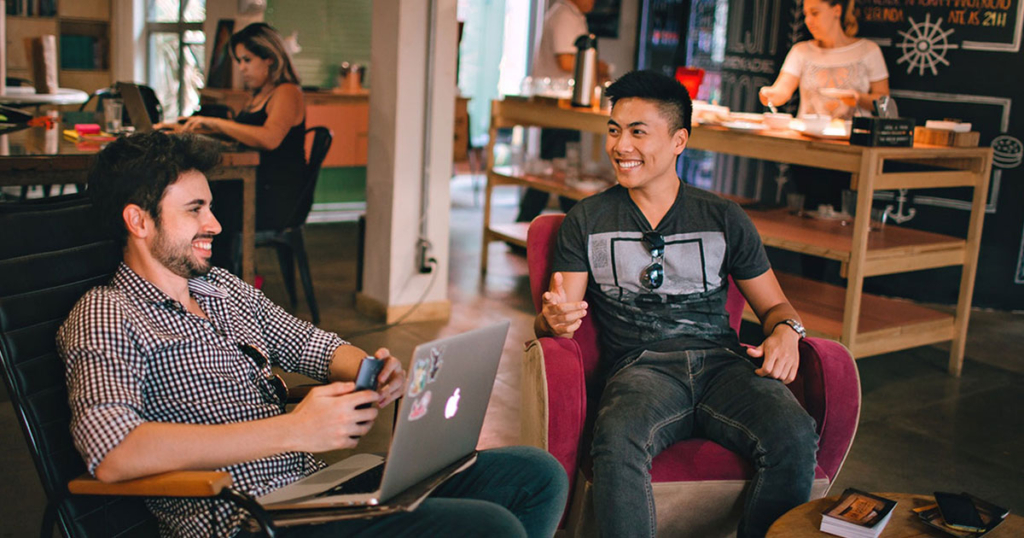 two people chatting over coffee in a cozy café, with others working in the background.