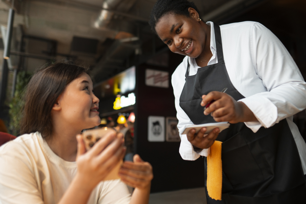 a photo of a smiling server at a restaurant while the guest looks up at her