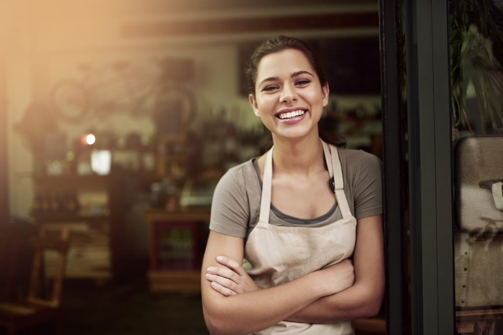 a photo of a smiling restaurant owner standing in the doorway with arms crossed.