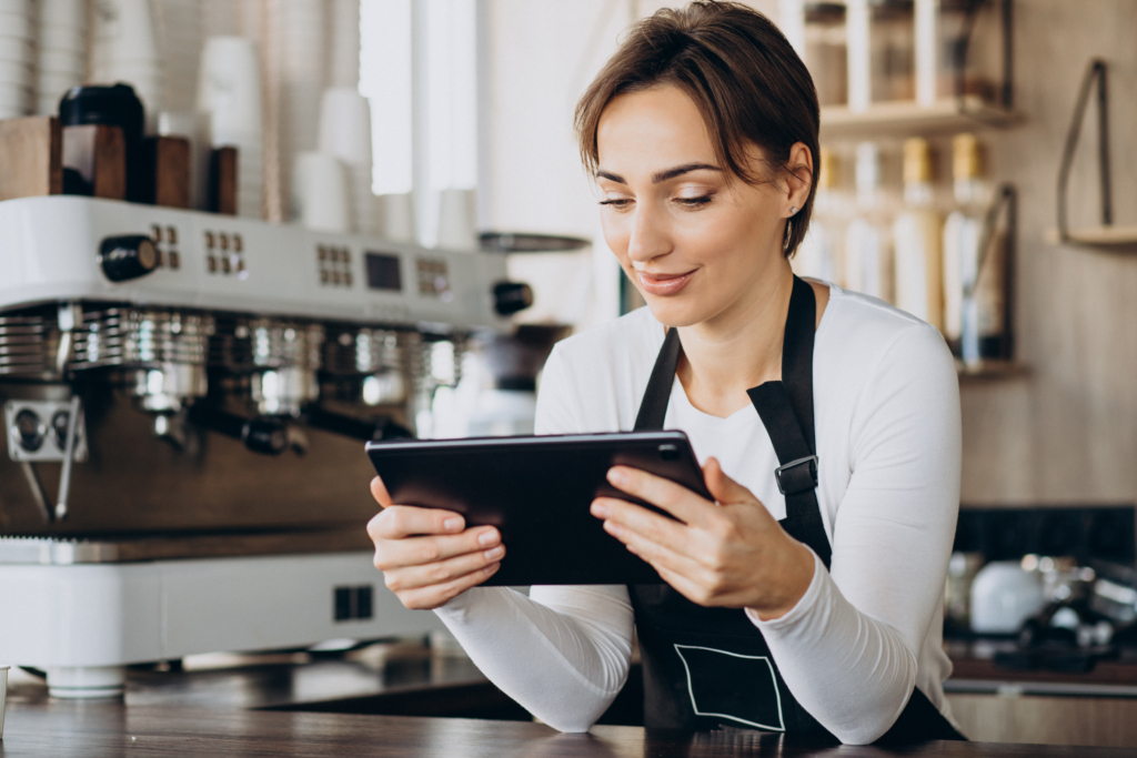Restaurant staff member using a tablet at the counter to manage online orders.