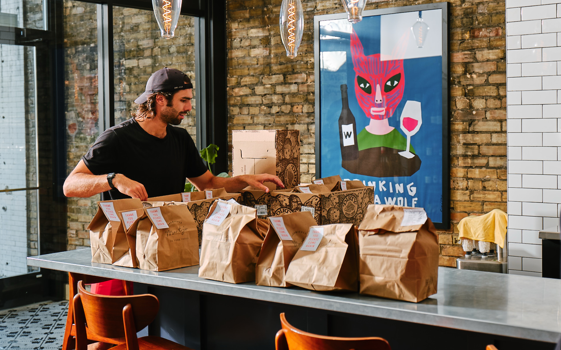 A restaurant worker organizes rows of takeout bags during a rush, showing how high-volume orders become easier to manage with centralized order aggregation instead of multiple tablets.