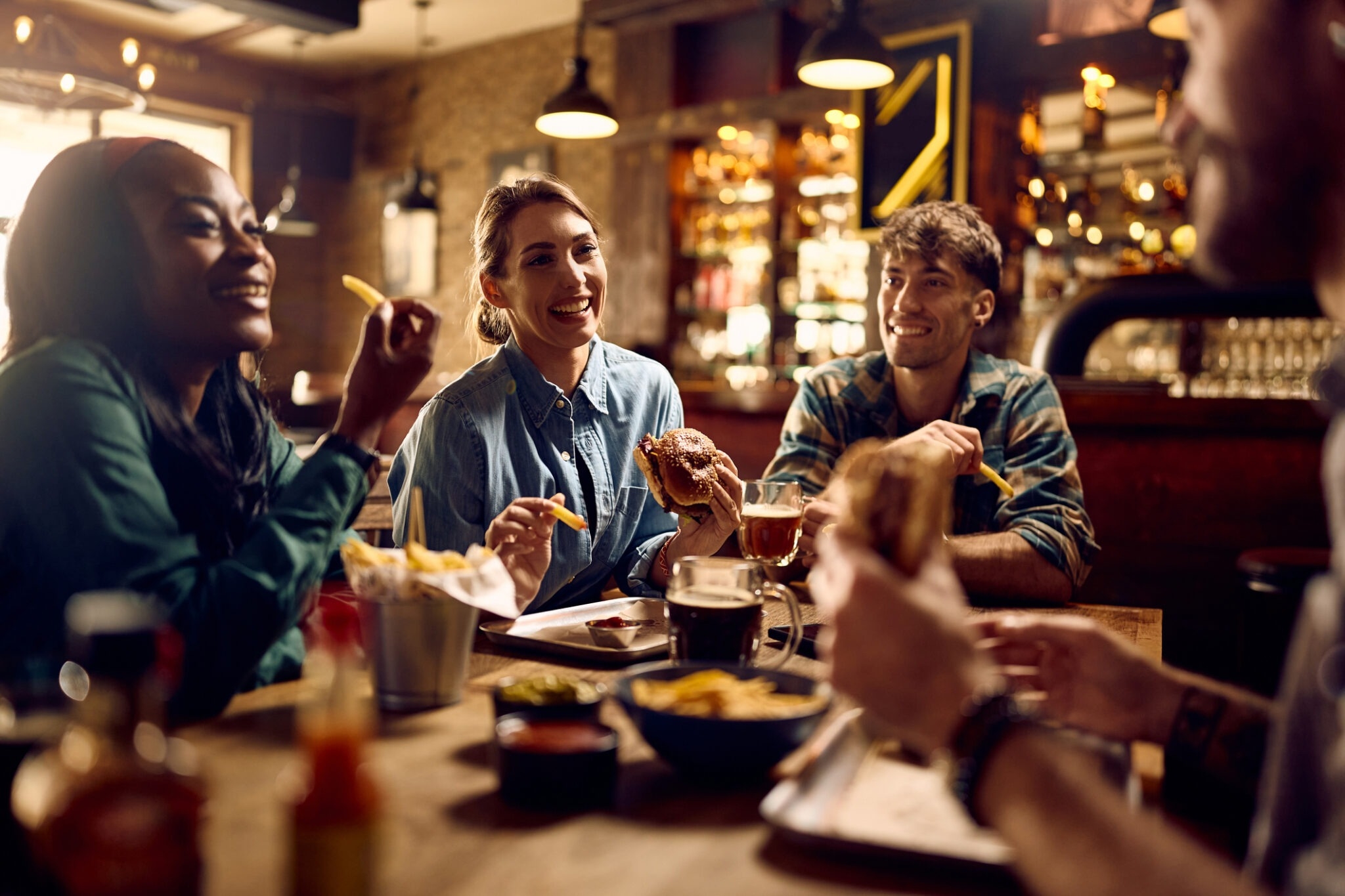 a photo of friends sharing burgers and drinks at a casual restaurant, capturing a social dining experience that encourages repeat customers