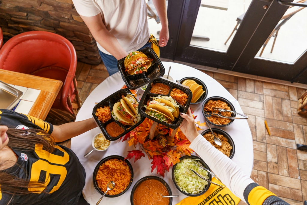 Overhead view of a group sharing catering trays, showing the group ordering opportunity independent restaurants can grow with direct online ordering