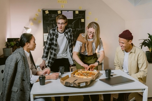  A group of coworkers sharing a pizza during an office lunch, representing the everyday corporate catering orders independent restaurants can capture with direct online ordering