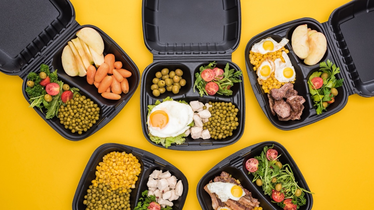 Five individual boxed catering meals with proteins, vegetables, and sides, showing the packaged catering format independent restaurants can offer for group and corporate orders