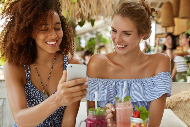 Two restaurant guests looking at a phone together, representing customer engagement through email and SMS marketing
