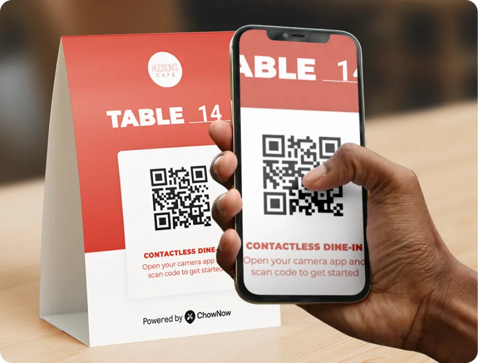 Guest scanning a QR code on a restaurant table tent with a phone to access contactless dine-in ordering