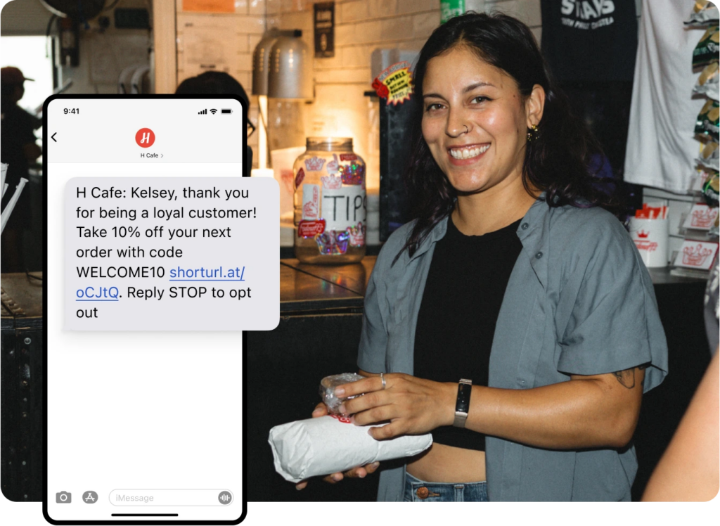 Restaurant staff member beside a phone screen showing a promotional SMS message for a loyal customer discount