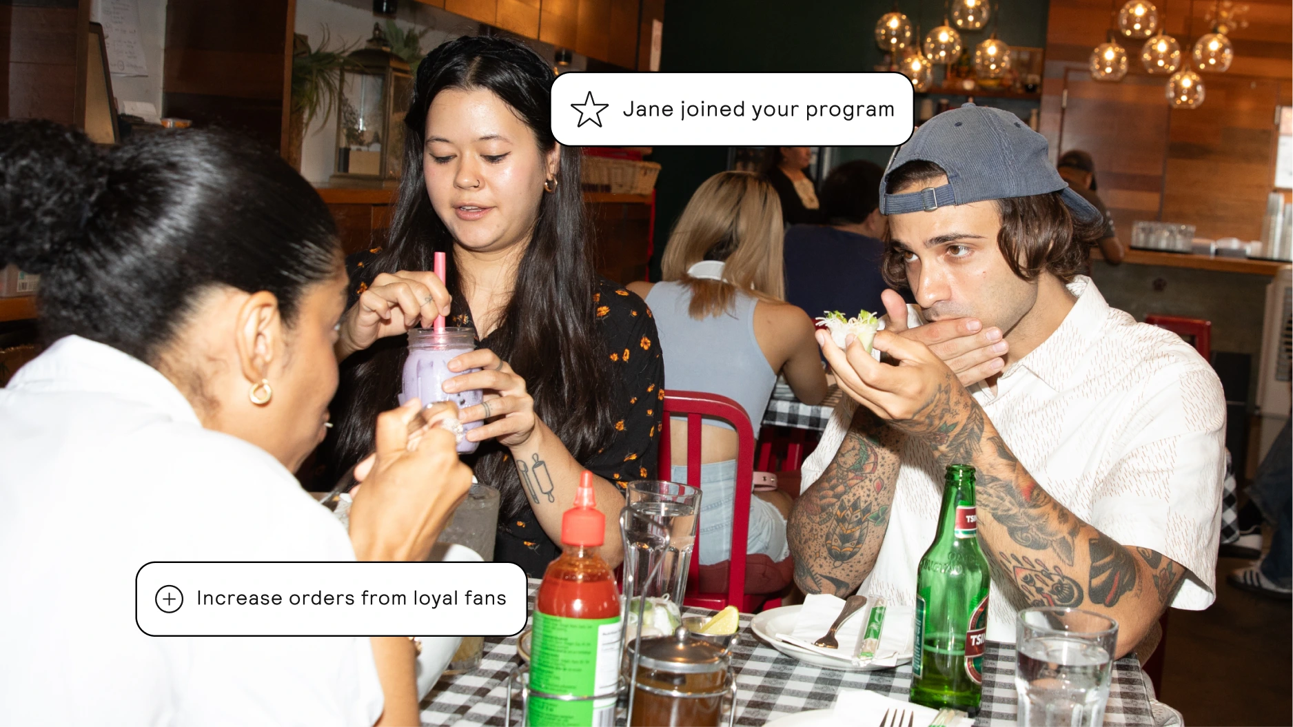 Guests dining together at a restaurant with loyalty program graphics, illustrating how restaurants can drive repeat orders from loyal customers.