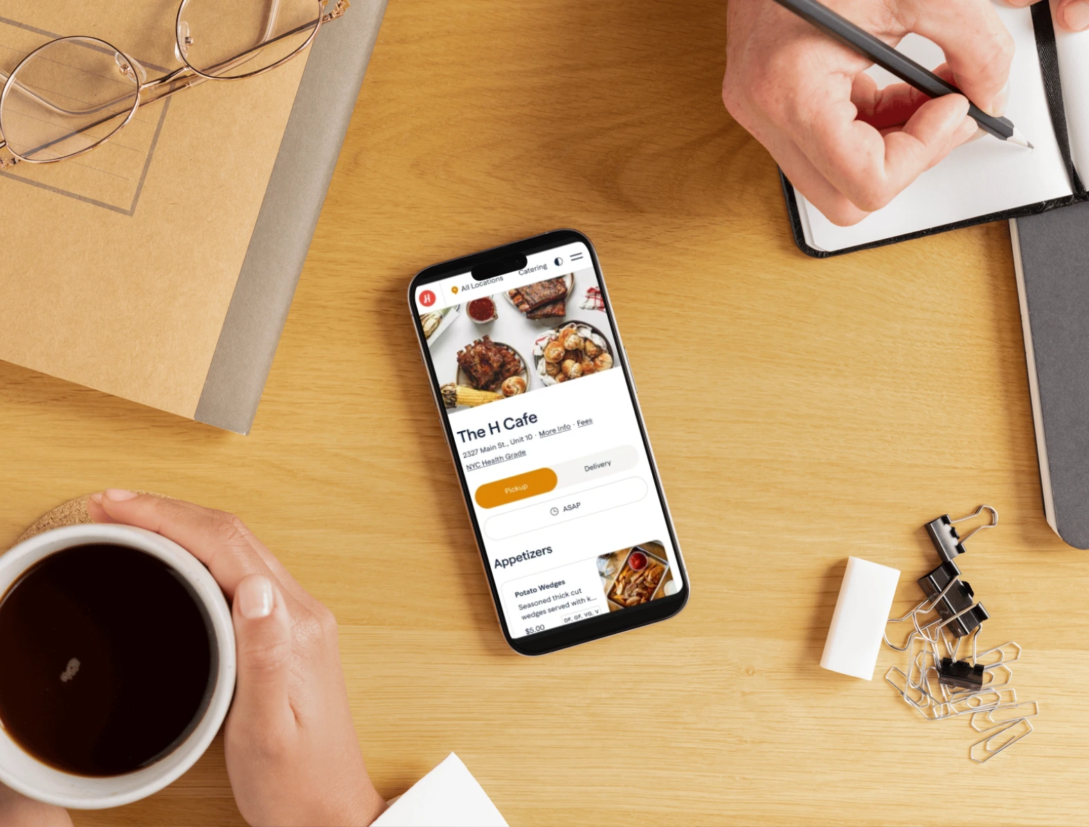 Restaurant online ordering app displayed on a smartphone on a desk, showing a branded restaurant storefront for pickup and delivery.