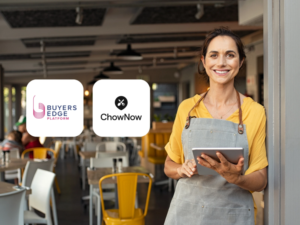 Smiling restaurant owner using a tablet in a dining room, with Buyers Edge Platform and ChowNow logos shown together.
