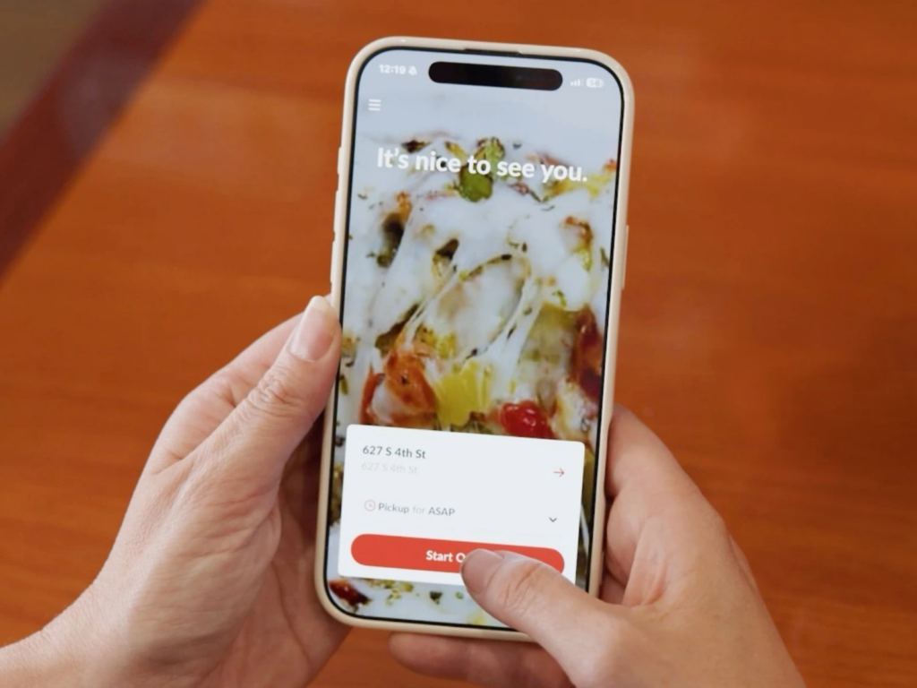 Hand holding a phone displaying the ChowNow ordering app welcome screen, 'It's nice to see you,' with a pickup option and Start Order button
