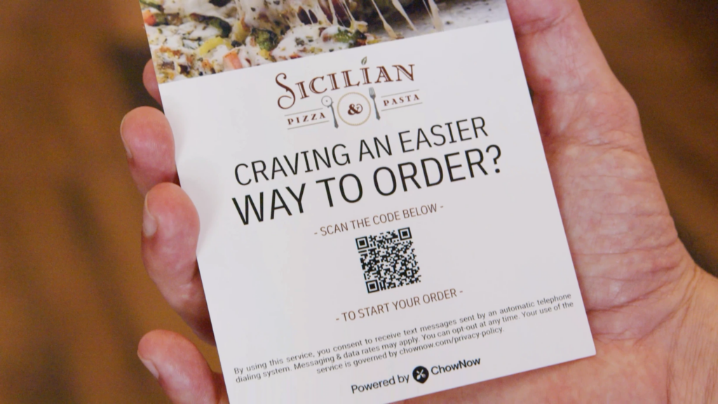 A Sicilian Pizza & Pasta table card reading 'Craving an easier way to order?' with a QR code to start a ChowNow direct order.